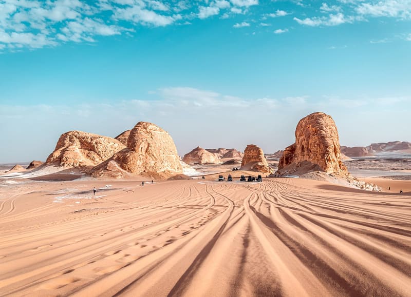 Grandi rocce calcaree dorate e dune solcate da tracce nella valle di Agabat