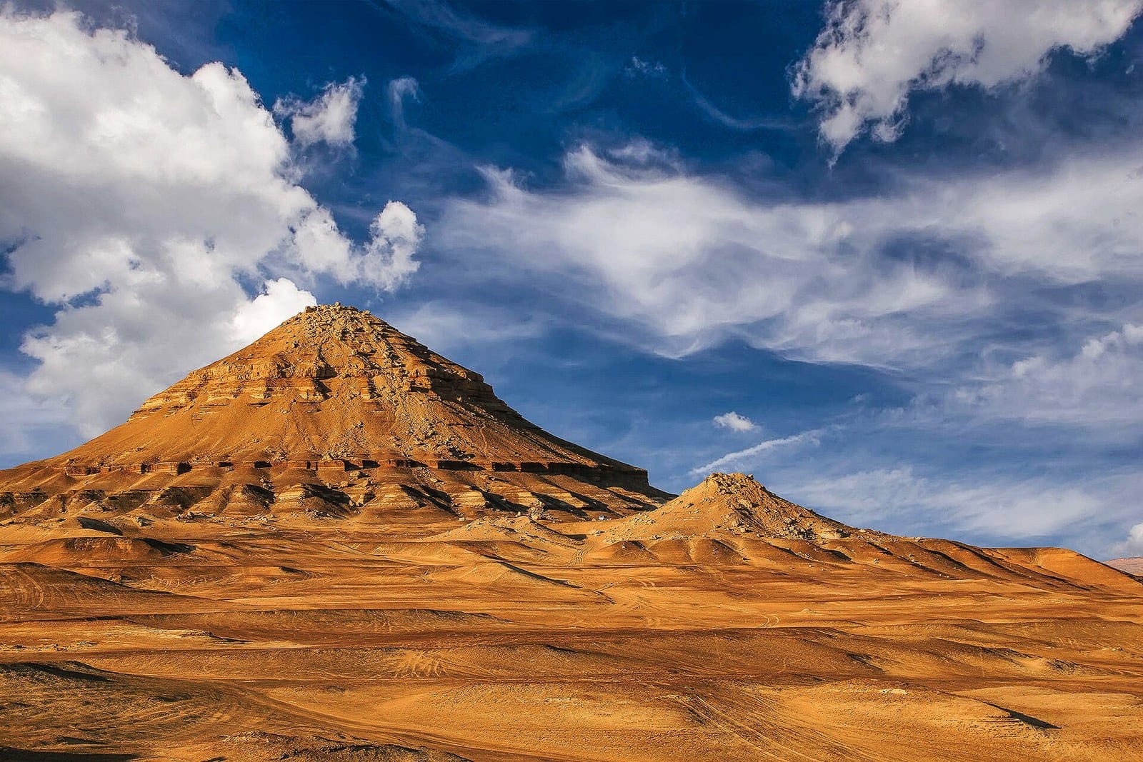 Montagna di sabbia dorata sotto un cielo azzurro con nuvole nell'oasi di Bahariya