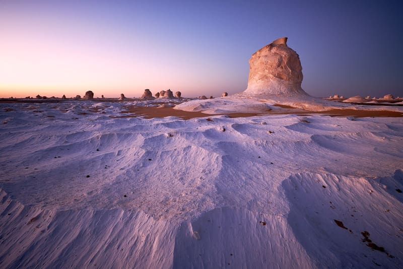 Formazioni di gesso del Deserto Bianco tinte di rosa e viola all'alba