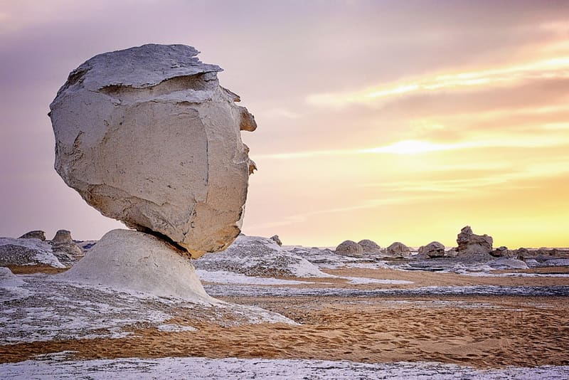 Roccia calcarea a forma di testa sotto un cielo rosa e dorato nel Deserto Bianco