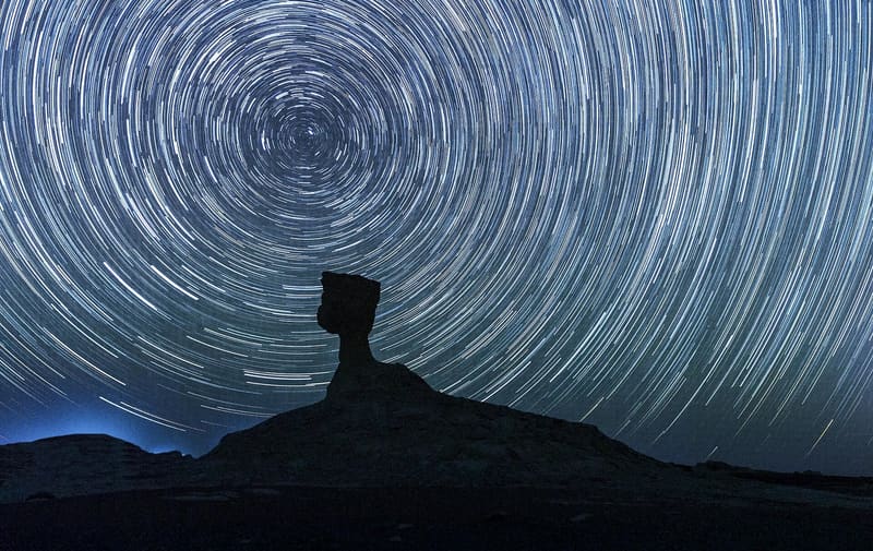 Scia circolare delle stelle sopra la sagoma di una roccia a fungo nel Deserto Bianco