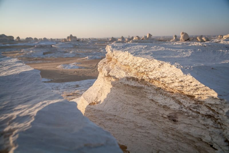 Primo piano della superficie scolpita dal vento del gesso bianco al tramonto
