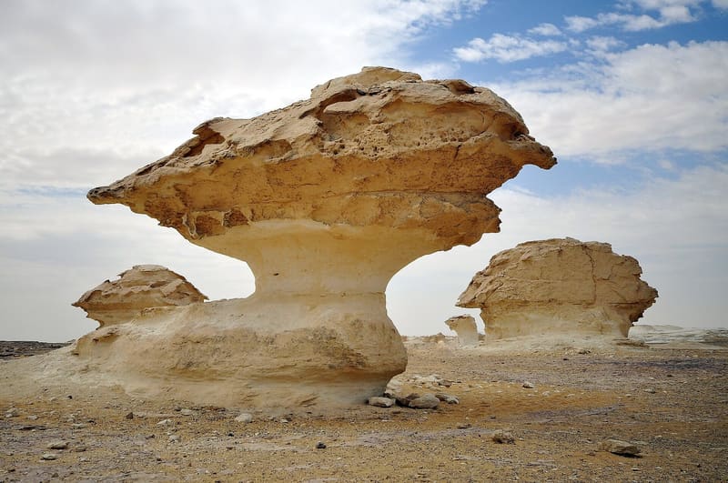 Grande roccia a fungo erosa dal vento sotto un cielo con nuvole nel Deserto Bianco