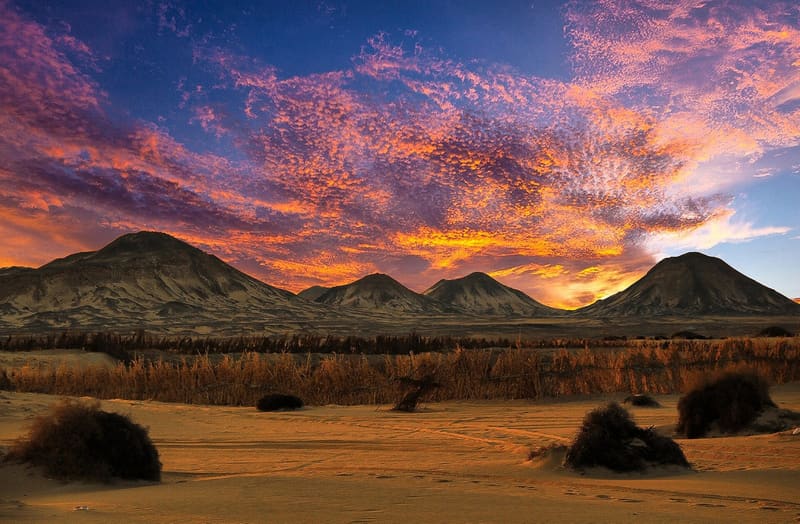 Colline vulcaniche del Deserto Nero sotto un cielo infuocato al tramonto vicino a Bahariya