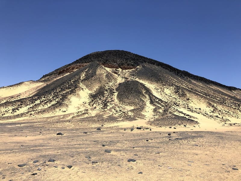 Collina coperta di pietre vulcaniche nere su sabbia dorata nel Deserto Nero