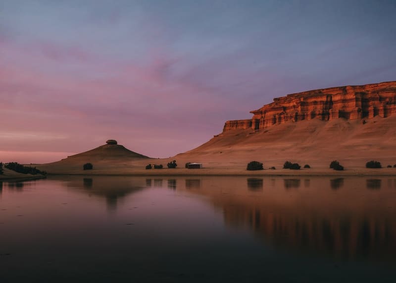 Il Lago Magico riflette le scogliere rosse al crepuscolo nel deserto del Fayoum