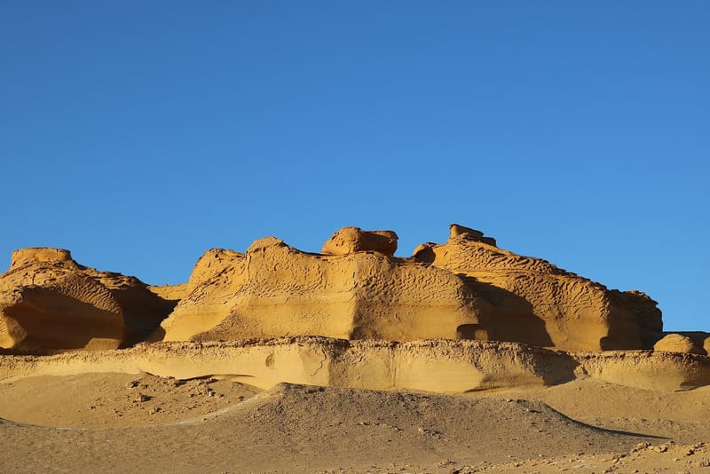 Rocce di arenaria scolpite dal vento sotto un cielo limpido nella Valle delle Balene