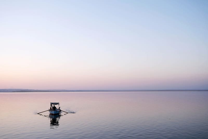 Barca di pescatori sulle acque calme del Lago Qarun nella luce rosa del crepuscolo