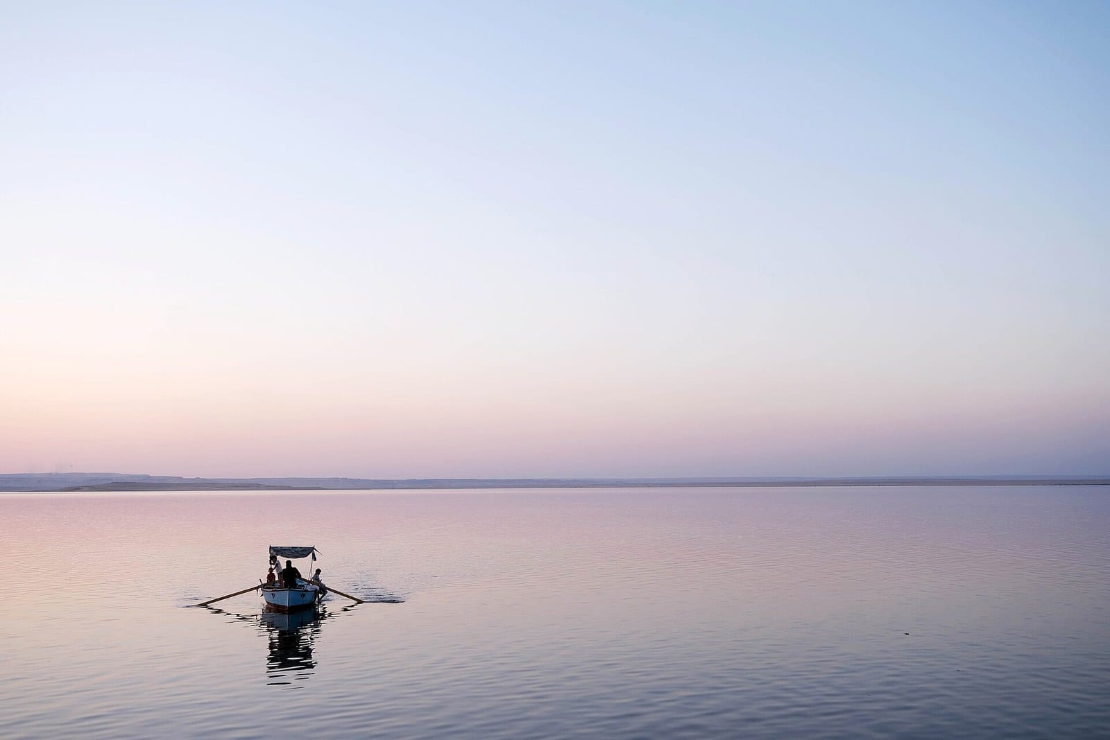 Barca di pescatori sulle acque calme del Lago Qarun nella luce rosa del crepuscolo